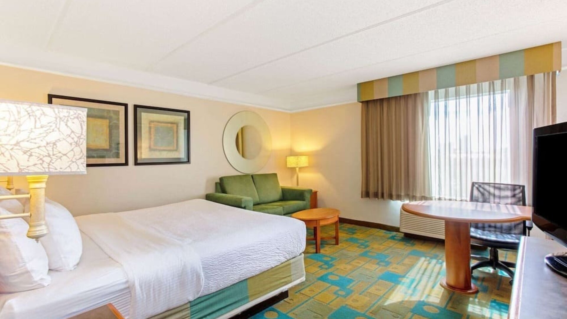 Bright guest room featuring a king-size bed, a comfortable seating area and abundant natural light at La Quinta Inn & Suites By Wyndham Orlando I Drive/Conv Ctr.