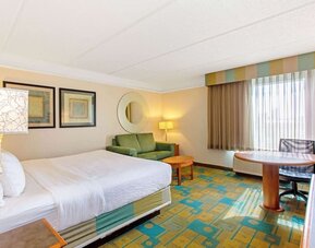 Bright guest room featuring a king-size bed, a comfortable seating area and abundant natural light at La Quinta Inn & Suites By Wyndham Orlando I Drive/Conv Ctr.