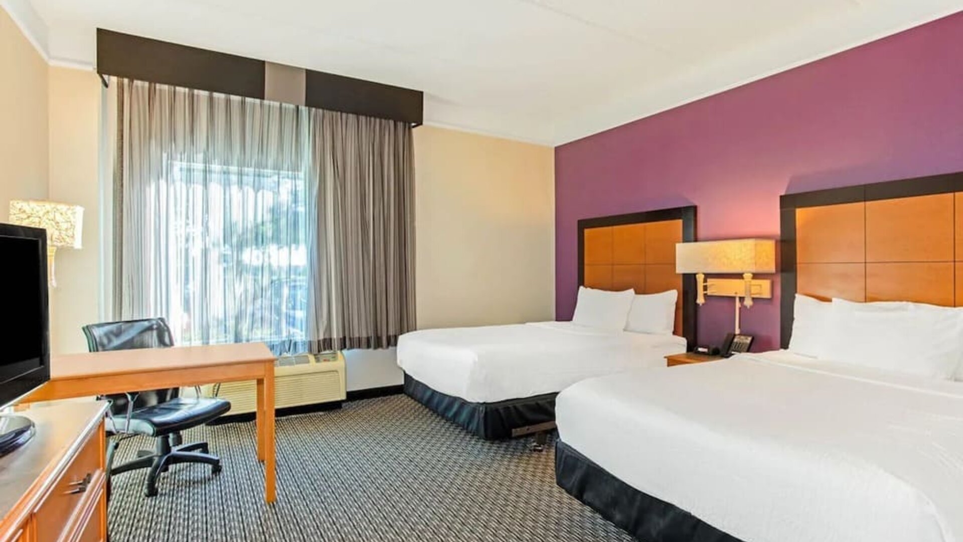 Guest room featuring two double beds, a dedicated workstation and comfortable accommodations for families or groups at La Quinta Inn & Suites By Wyndham Orlando I Drive/Conv Ctr.