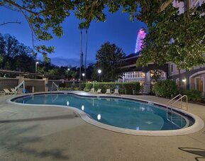 Resort-style outdoor pool featuring curved design, surrounding lounge chairs and evening views at La Quinta Inn & Suites By Wyndham Orlando I Drive/Conv Ctr.