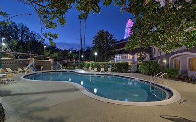 Resort-style outdoor pool featuring curved design, surrounding lounge chairs and evening views at La Quinta Inn & Suites By Wyndham Orlando I Drive/Conv Ctr.