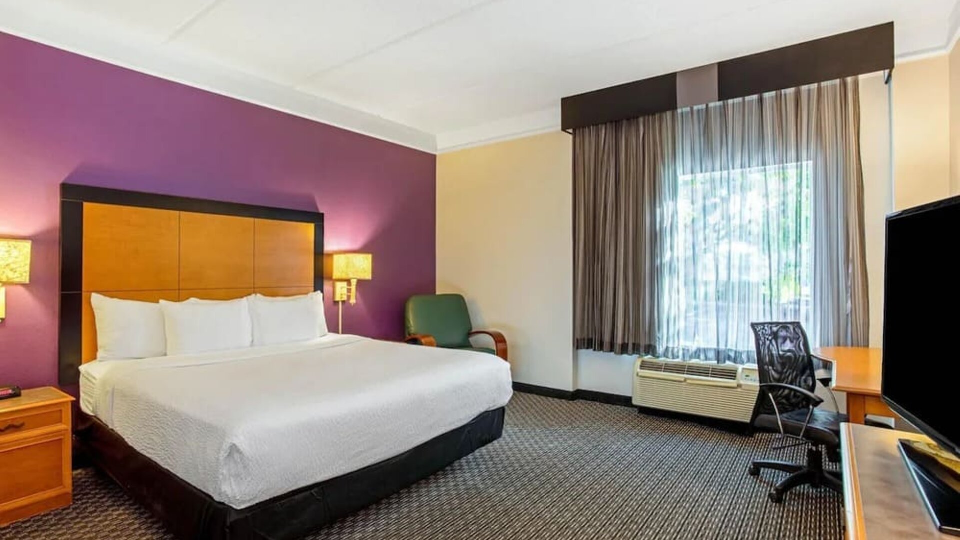 Comfortable guest room featuring a king-size bed, a dedicated workspace and contemporary décor at La Quinta Inn & Suites By Wyndham Orlando I Drive/Conv Ctr.