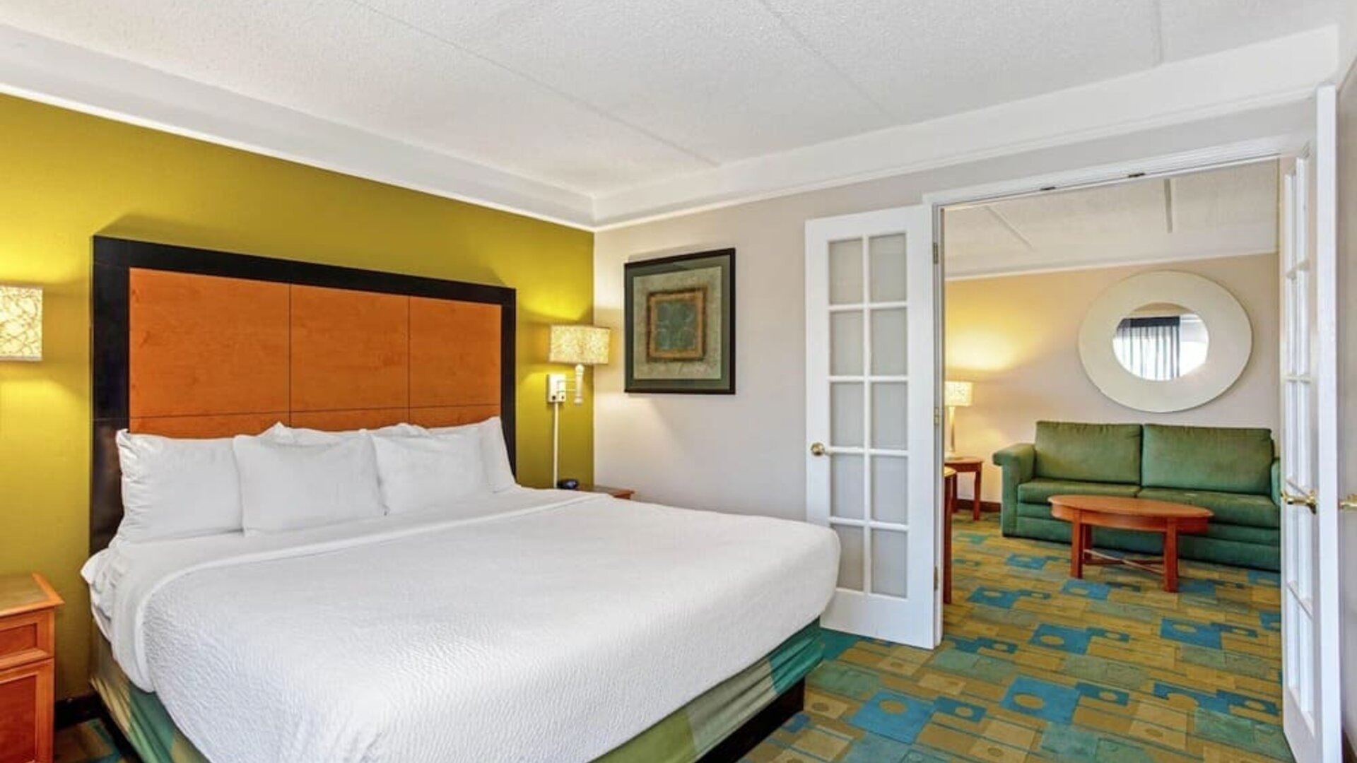 Spacious suite featuring a king-size bed, a separate living area and contemporary furnishings at La Quinta Inn & Suites By Wyndham Orlando I Drive/Conv Ctr.