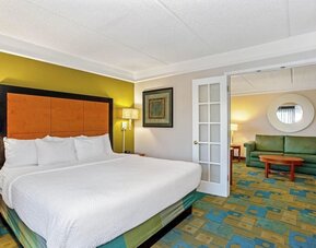 Spacious suite featuring a king-size bed, a separate living area and contemporary furnishings at La Quinta Inn & Suites By Wyndham Orlando I Drive/Conv Ctr.