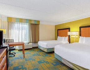 Bright guest room featuring two double beds, a dedicated workspace and large windows with natural light at La Quinta Inn & Suites By Wyndham Orlando I Drive/Conv Ctr.