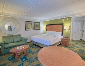 Comfortable suite featuring a king-size bed, a sofa seating area and an open-concept layout at La Quinta Inn & Suites By Wyndham Orlando I Drive/Conv Ctr.