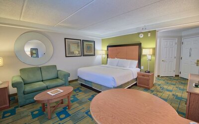 Comfortable suite featuring a king-size bed, a sofa seating area and an open-concept layout at La Quinta Inn & Suites By Wyndham Orlando I Drive/Conv Ctr.