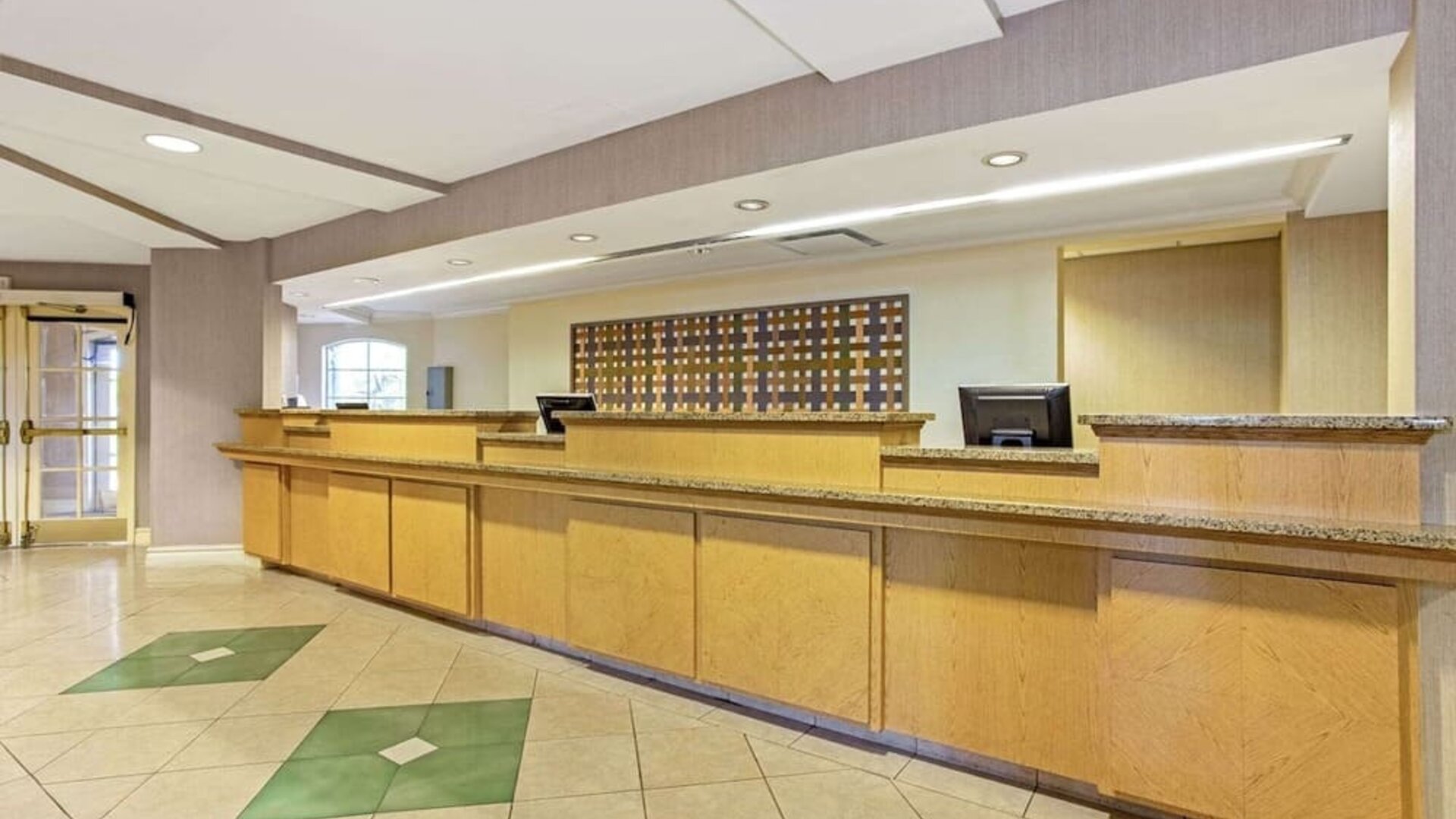 Reception area featuring an extended front desk, contemporary finishes and convenient guest services at La Quinta Inn & Suites By Wyndham Orlando I Drive/Conv Ctr.