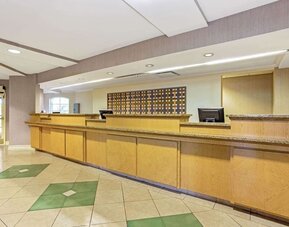 Reception area featuring an extended front desk, contemporary finishes and convenient guest services at La Quinta Inn & Suites By Wyndham Orlando I Drive/Conv Ctr.