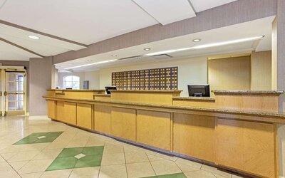 Reception area featuring an extended front desk, contemporary finishes and convenient guest services at La Quinta Inn & Suites By Wyndham Orlando I Drive/Conv Ctr.