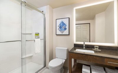 Modern bathroom featuring a spacious vanity, a glass-enclosed shower and neatly arranged towels at Candlewood Suites Meridian.