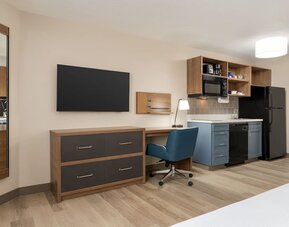 In-room workspace and kitchenette featuring a full-size refrigerator, microwave, dishwasher and dedicated desk area at Candlewood Suites Meridian.
