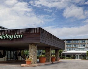 Covered hotel entrance featuring stone columns, landscaped planters and convenient drop-off access at Holiday Inn Toronto Airport East.