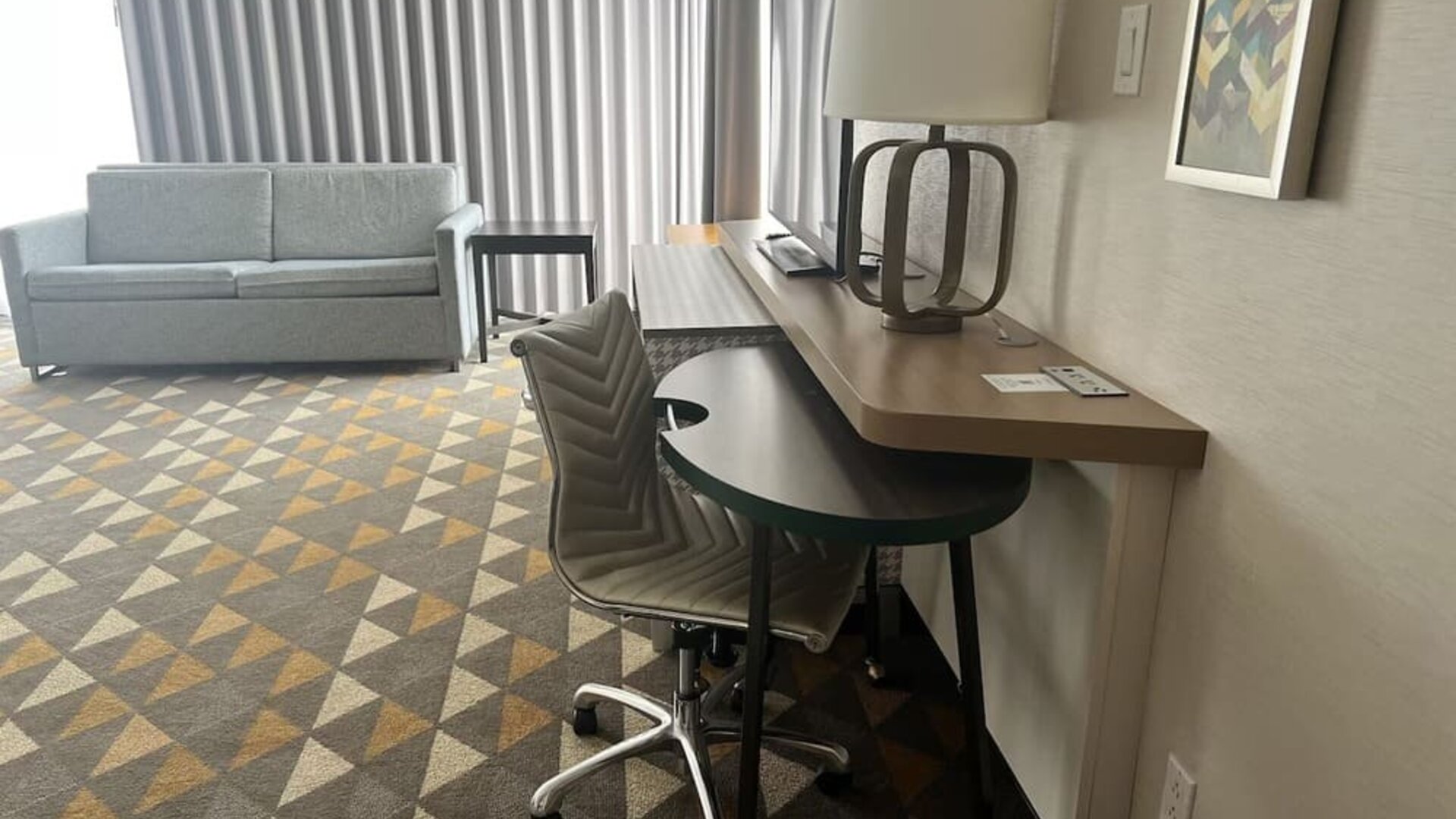 In-room workspace featuring a large desk, ergonomic seating and a comfortable lounge area with floor-to-ceiling window coverings at Holiday Inn Toronto Airport East.