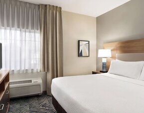 Guest room featuring a queen-size bed, natural light and contemporary furnishings designed for comfort at Candlewood Suites Boise.