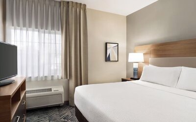 Guest room featuring a queen-size bed, natural light and contemporary furnishings designed for comfort at Candlewood Suites Boise.