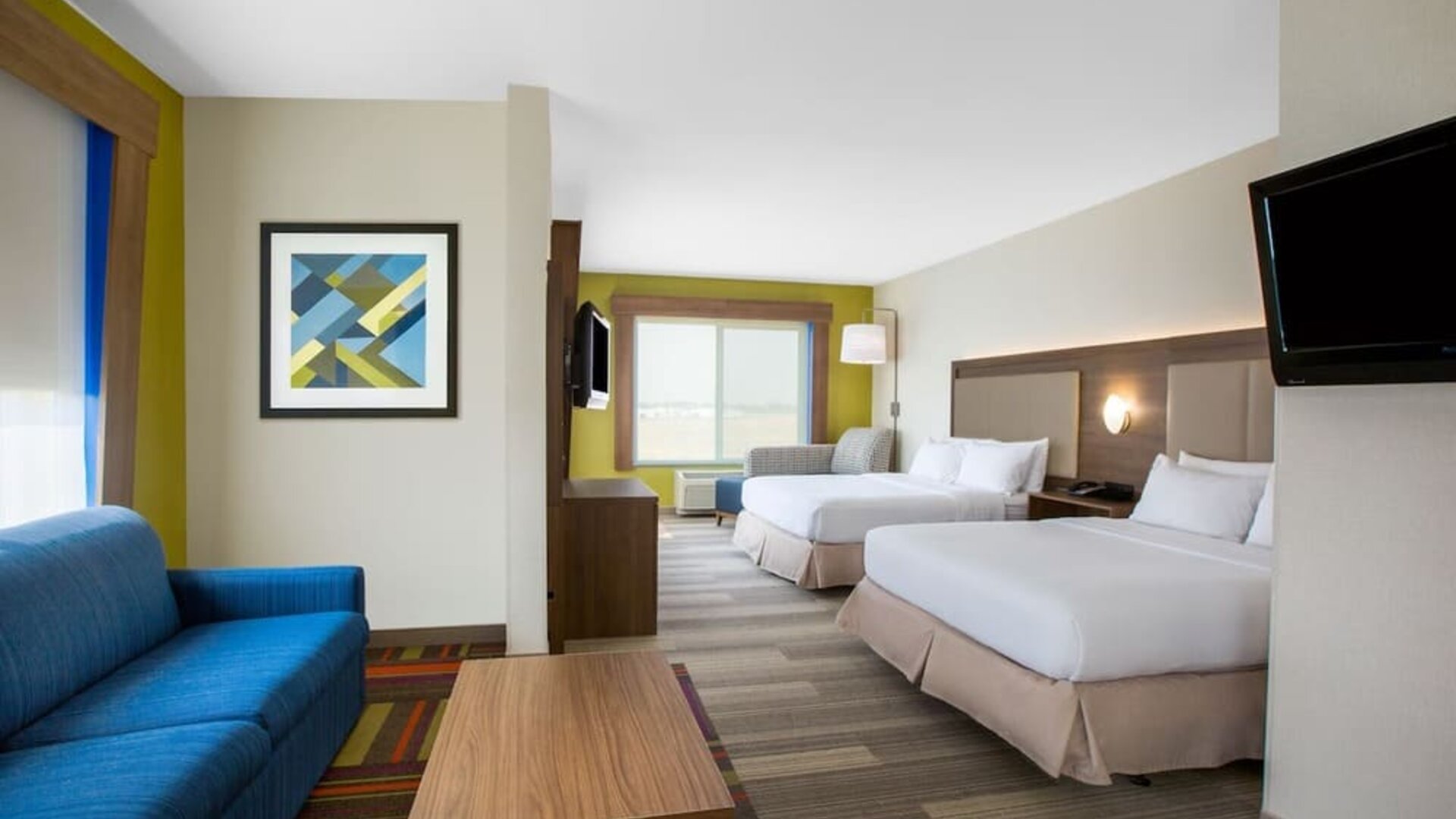 Spacious guest suite featuring two beds, a separate sitting area and contemporary furnishings at Holiday Inn Express & Suites Ontario.