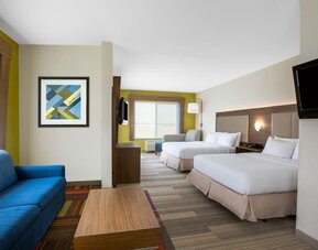 Spacious guest suite featuring two beds, a separate sitting area and contemporary furnishings at Holiday Inn Express & Suites Ontario.