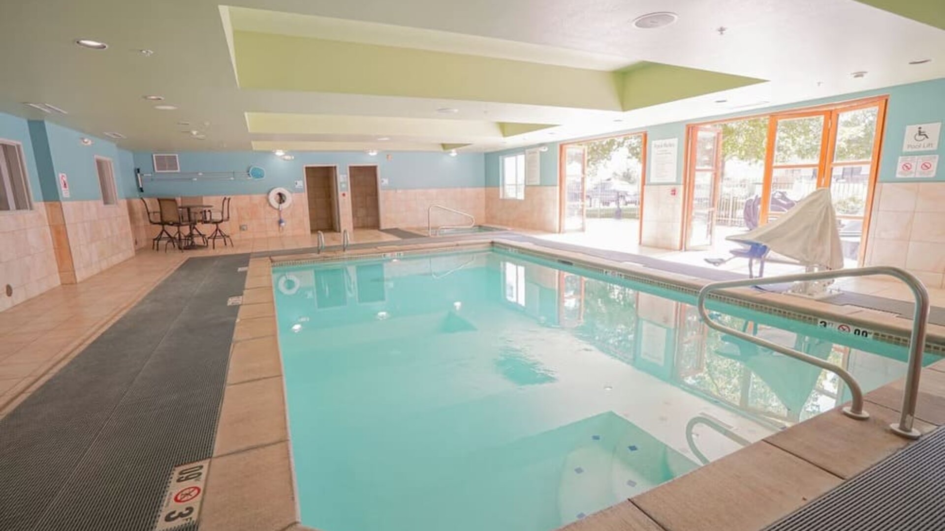 Indoor pool area featuring a spacious swimming pool, accessible features and comfortable seating at Holiday Inn Express & Suites Ontario.