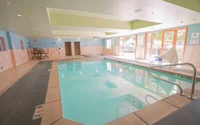 Indoor pool area featuring a spacious swimming pool, accessible features and comfortable seating at Holiday Inn Express & Suites Ontario.