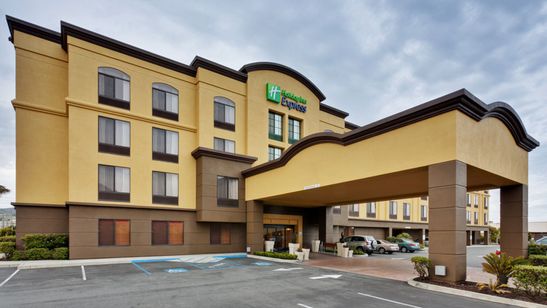 Hotel exterior featuring a covered entrance, contemporary architecture and convenient on-site parking at Holiday Inn Express SFO Airport North.