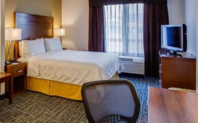 Guest room featuring a king-size bed, a dedicated workspace, a flat-screen television and natural light at Holiday Inn Express SFO Airport North.