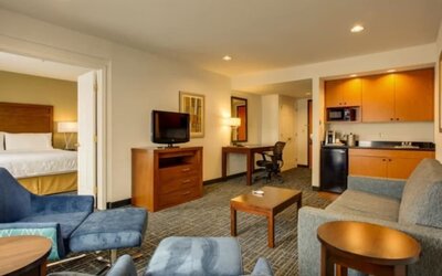 One-bedroom suite featuring a separate bedroom, a living area, a kitchenette and comfortable seating at Holiday Inn Express SFO Airport North.
