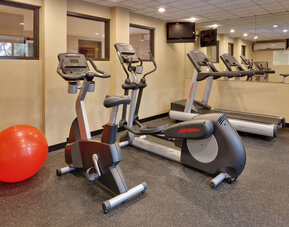 Fitness center featuring cardio equipment, mirrored walls and space for stretching and exercise at Holiday Inn Express SFO Airport North.