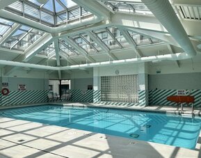 Indoor swimming pool featuring a glass atrium ceiling, abundant natural light and a relaxing atmosphere at Holiday Inn Toronto Airport East.