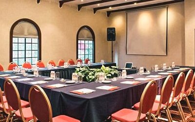 Meeting room arranged in a U-shaped conference layout with presentation equipment and banquet seating at Hotel Geneve.
