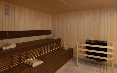 Wood-paneled hotel sauna with tiered wooden benches, folded towels, sauna heater and temperature gauges.