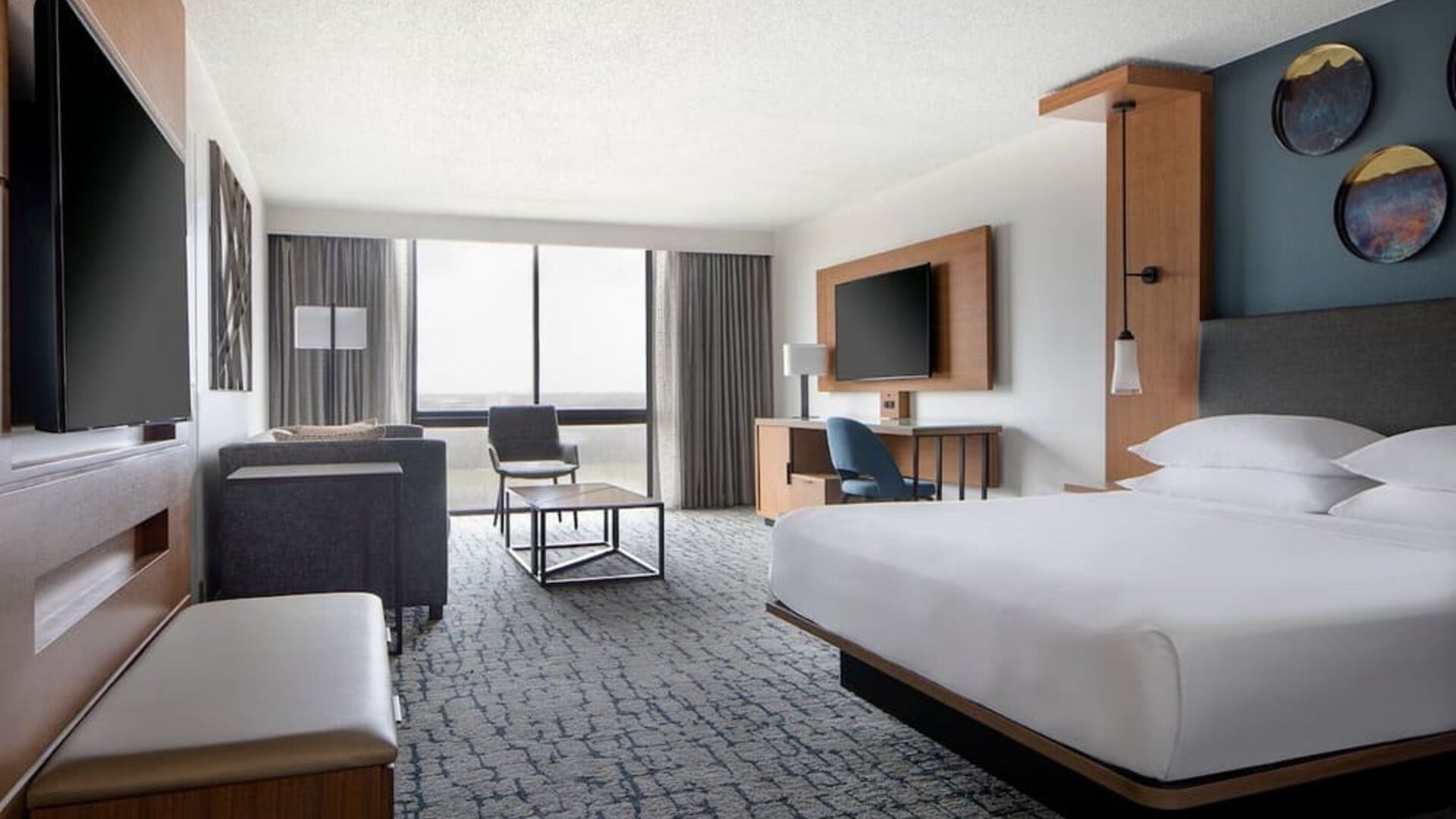 Guest room featuring a king bed, comfortable seating, natural light, and modern amenities at Houston Marriott South at Hobby Airport.