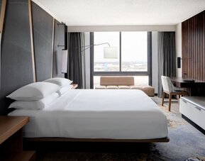 Guest room featuring a king bed, floor-to-ceiling windows, a workspace, and modern décor at Houston Marriott South at Hobby Airport.