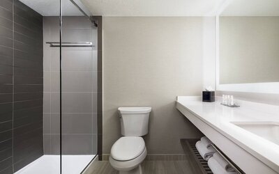 Bathroom featuring a walk-in shower, illuminated vanity, and contemporary fixtures at Houston Marriott South at Hobby Airport.