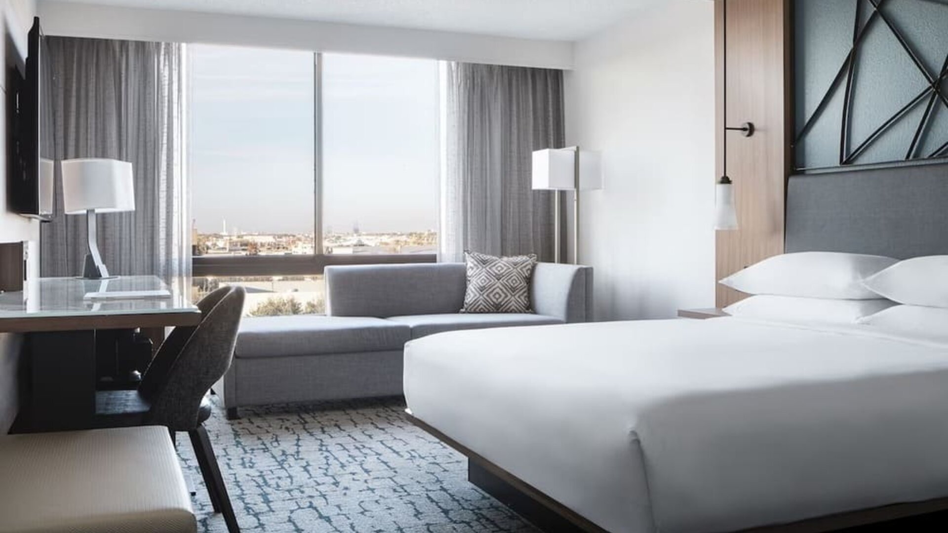 Guest room featuring a chaise lounge, city views, a workspace, and contemporary furnishings at Houston Marriott South at Hobby Airport.