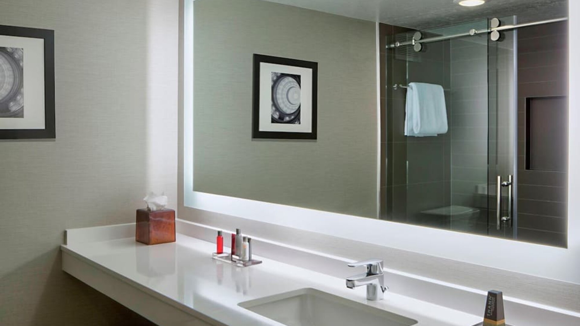 Bathroom featuring a modern vanity, illuminated mirror, glass-enclosed shower, and premium amenities at Houston Marriott South at Hobby Airport.