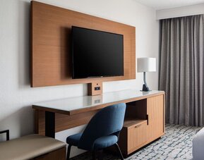 In-room workspace featuring a spacious desk, mounted television, and ergonomic seating at Houston Marriott South at Hobby Airport.