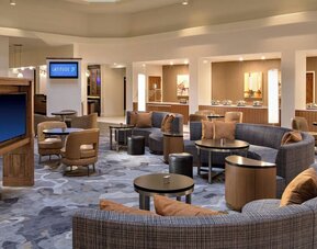 Lobby area featuring comfortable seating, gathering spaces, and access to dining amenities at Houston Marriott South at Hobby Airport.