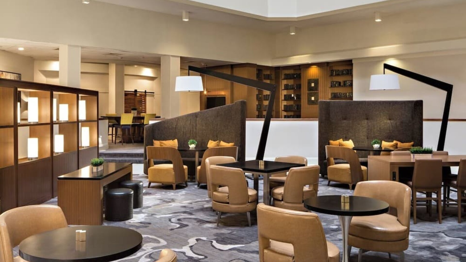 Lobby seating area featuring semi-private seating, communal tables, and contemporary décor at Houston Marriott South at Hobby Airport.