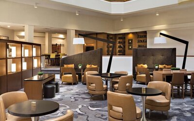 Lobby seating area featuring semi-private seating, communal tables, and contemporary décor at Houston Marriott South at Hobby Airport.