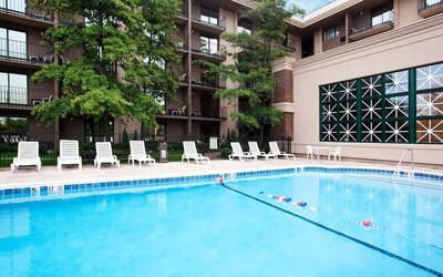 Outdoor swimming pool featuring lounge chairs, landscaped surroundings, and guest accommodations overlooking the pool area at Holiday Inn Express Rolling Meadows-Schaumburg.