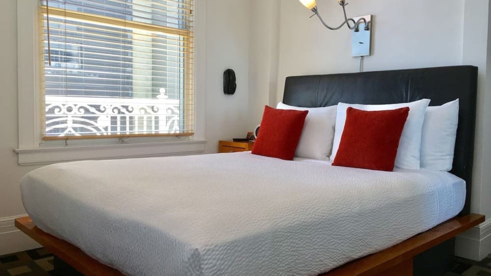 Guest room featuring a platform bed, oversized windows, accent pillows, and abundant natural light at The Mosser Hotel.
