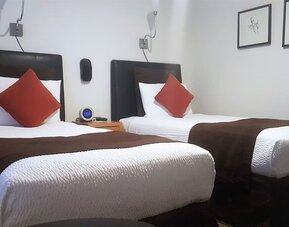 Guest room featuring two twin beds, minimalist décor, wall-mounted lighting, and modern furnishings at The Mosser Hotel.