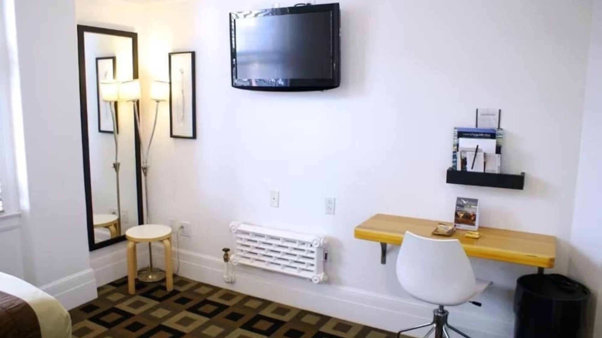 Guest room workspace featuring a wall-mounted television, a compact desk, modern seating, and a dedicated work area at The Mosser Hotel.