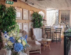 Outdoor patio featuring wicker seating, lush greenery, floral arrangements, and a relaxed terrace atmosphere at Cellai Boutique Hotel.