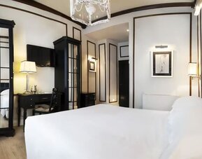 Spacious room featuring a large bed, decorative wall molding, mirrored wardrobes, and sophisticated furnishings at Cellai Boutique Hotel.