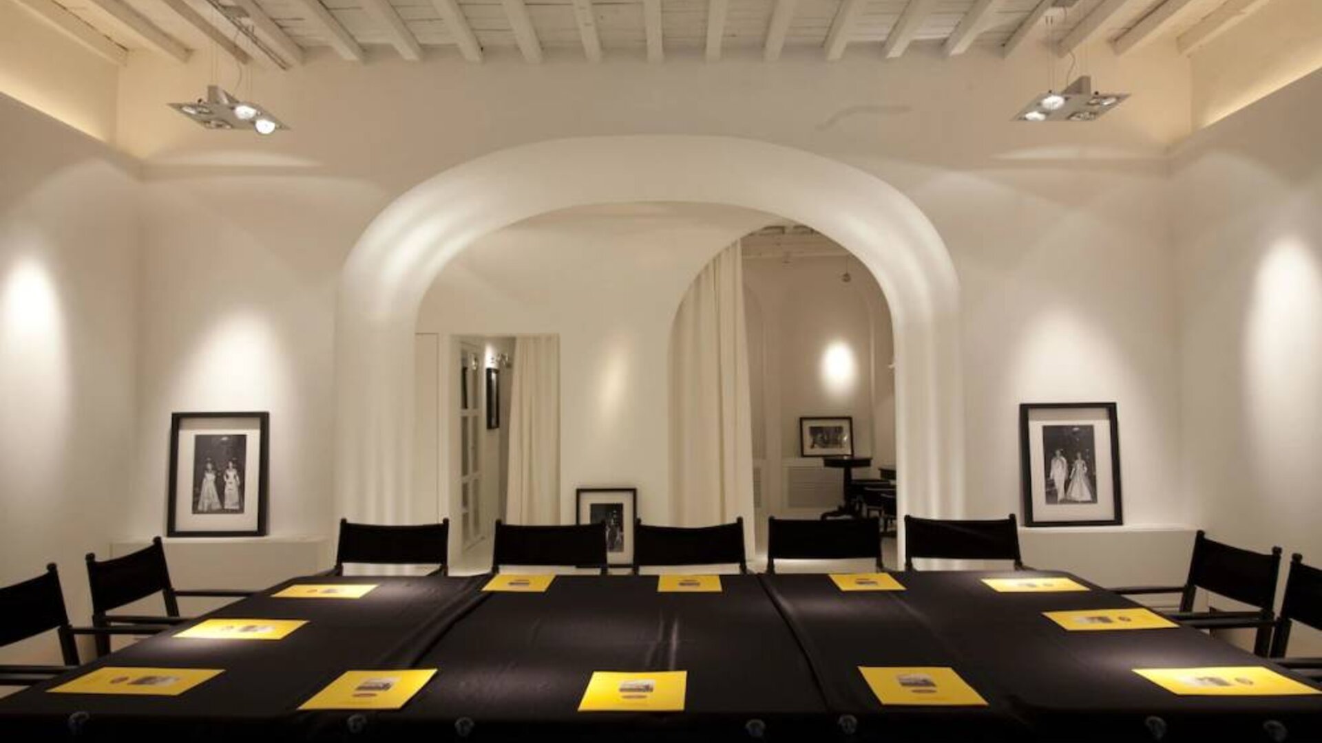 Meeting room featuring arched architecture, high ceilings with exposed beams, and a conference-style table setup at Cellai Boutique Hotel.