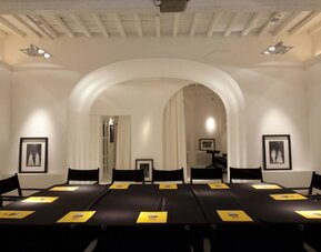 Meeting room featuring arched architecture, high ceilings with exposed beams, and a conference-style table setup at Cellai Boutique Hotel.