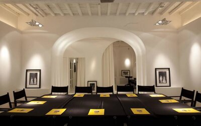 Meeting room featuring arched architecture, high ceilings with exposed beams, and a conference-style table setup at Cellai Boutique Hotel.