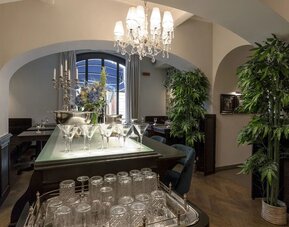 Bar area featuring crystal chandeliers, arched entryways, elegant glassware displays, and contemporary lounge seating at Cellai Boutique Hotel.